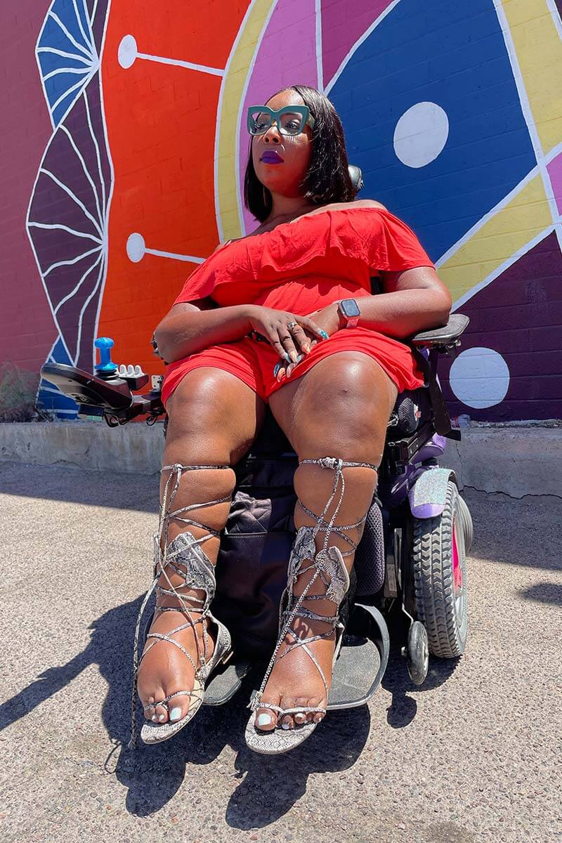 A picture of Andraéa Lavant unapologetically sat in her wheelchair rocking a summer romper